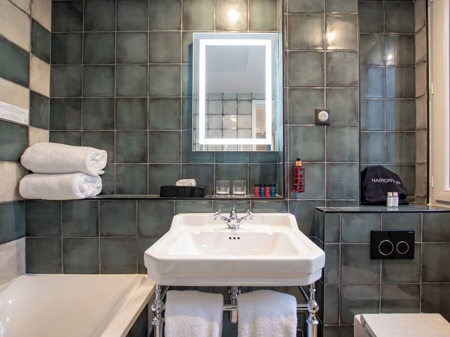 A modern bathroom with a white sink, a mirror, and a towel rack.