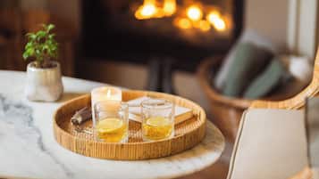 Ambiente acogedor en el interior con chimenea, una bandeja con vasos y una vela, y una pequeña planta en maceta.