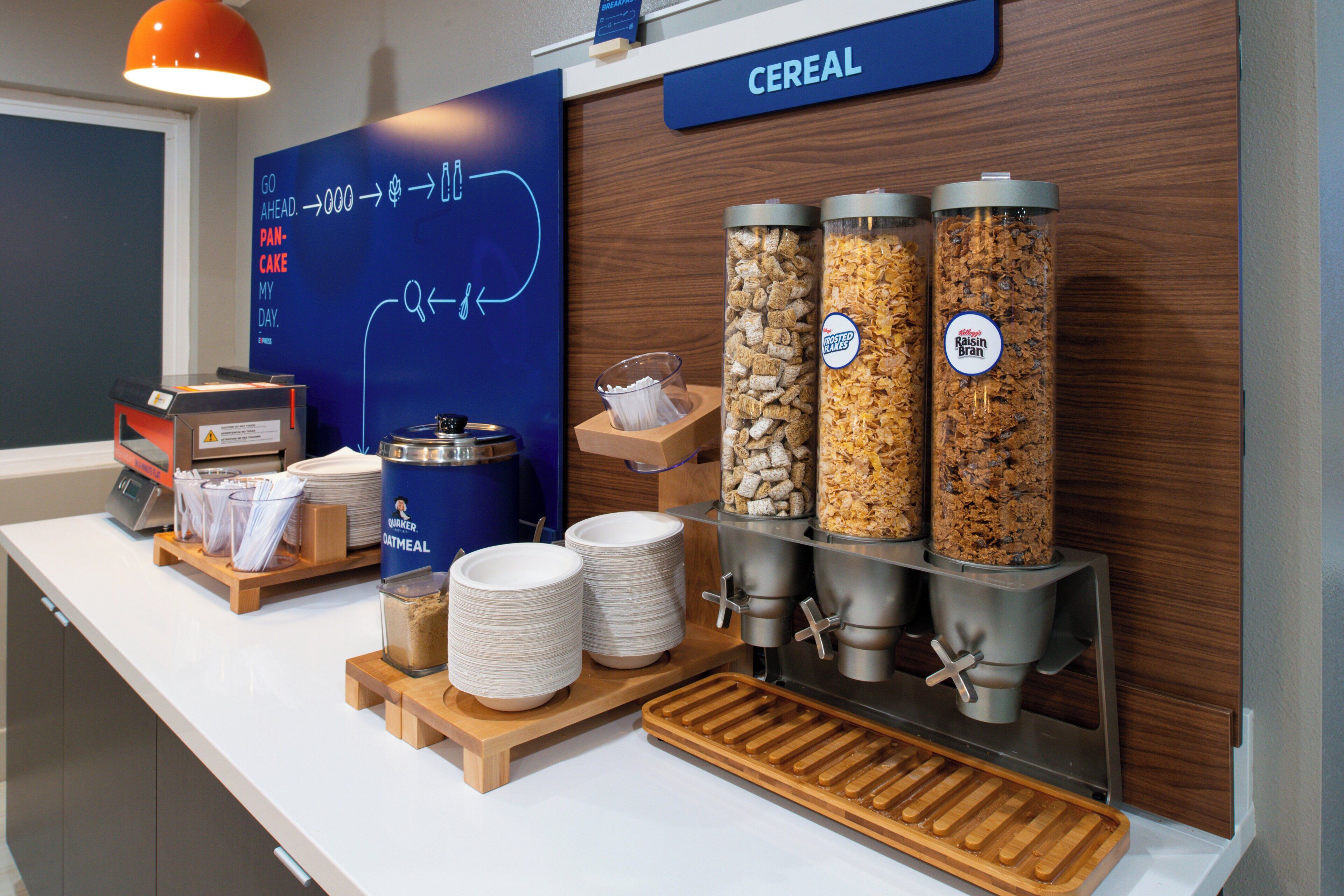 Una estación de desayuno con dispensadores de cereales, un cartel que indica las opciones de desayuno y un menú digital.