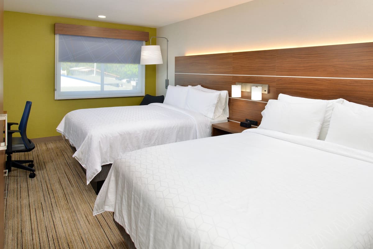A hotel room with two beds, a desk, and a chair.