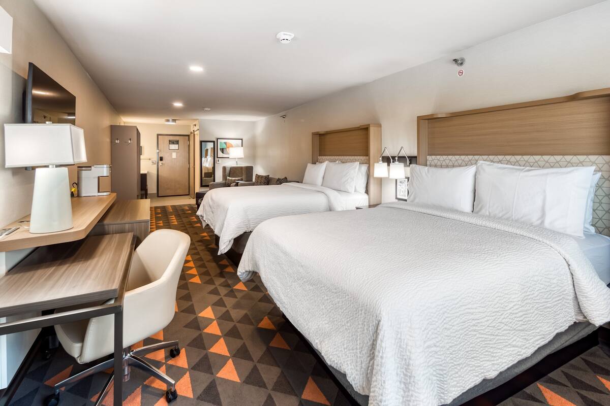 Een hotelkamer met twee bedden, een bureau, een stoel en een badkamer.
