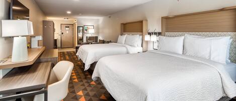Habitación de hotel con dos camas, un escritorio, una silla y baño.