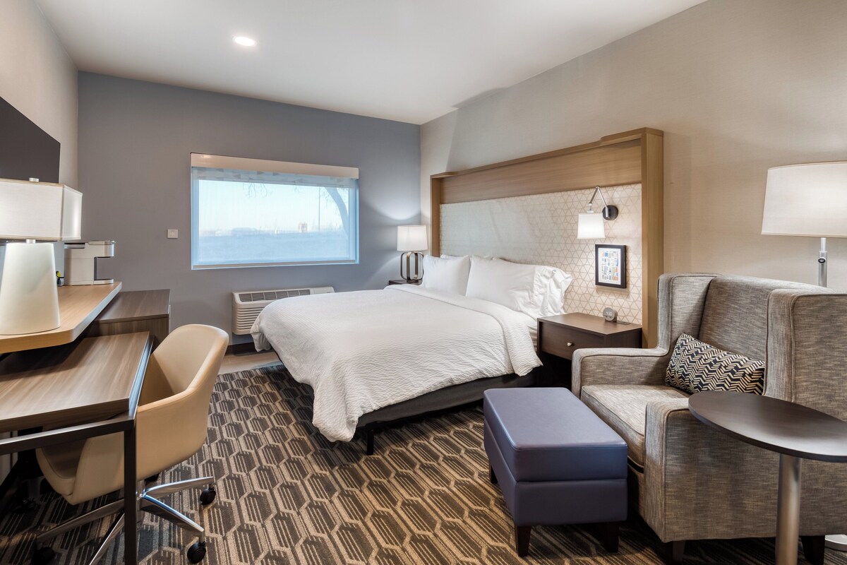 A hotel room with a bed, a desk, a chair, a sofa, and a small table.