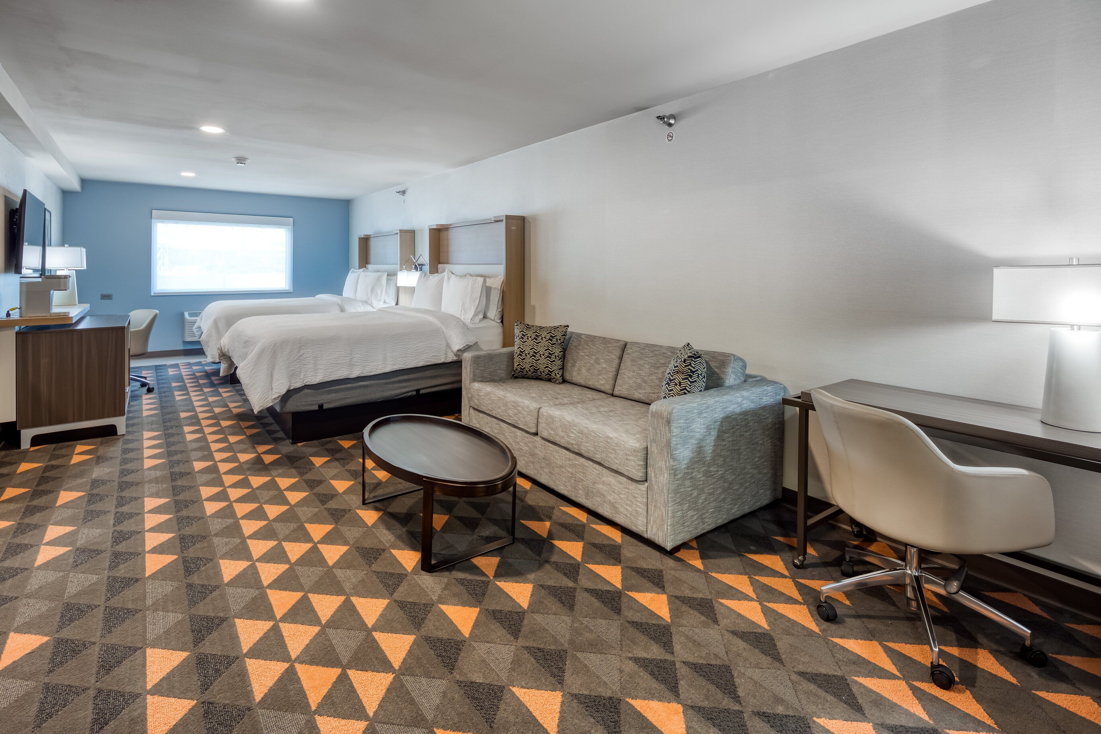 A hotel room with a bed, a sofa, a desk, and a chair.