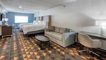 A hotel room with a bed, a sofa, a desk, and a chair.