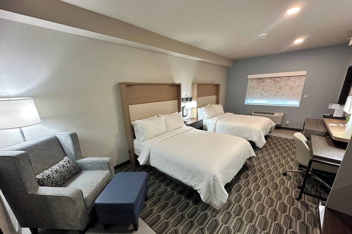 Een hotelkamer met twee bedden, een bureau, een stoel, een bank en een kleine tafel.