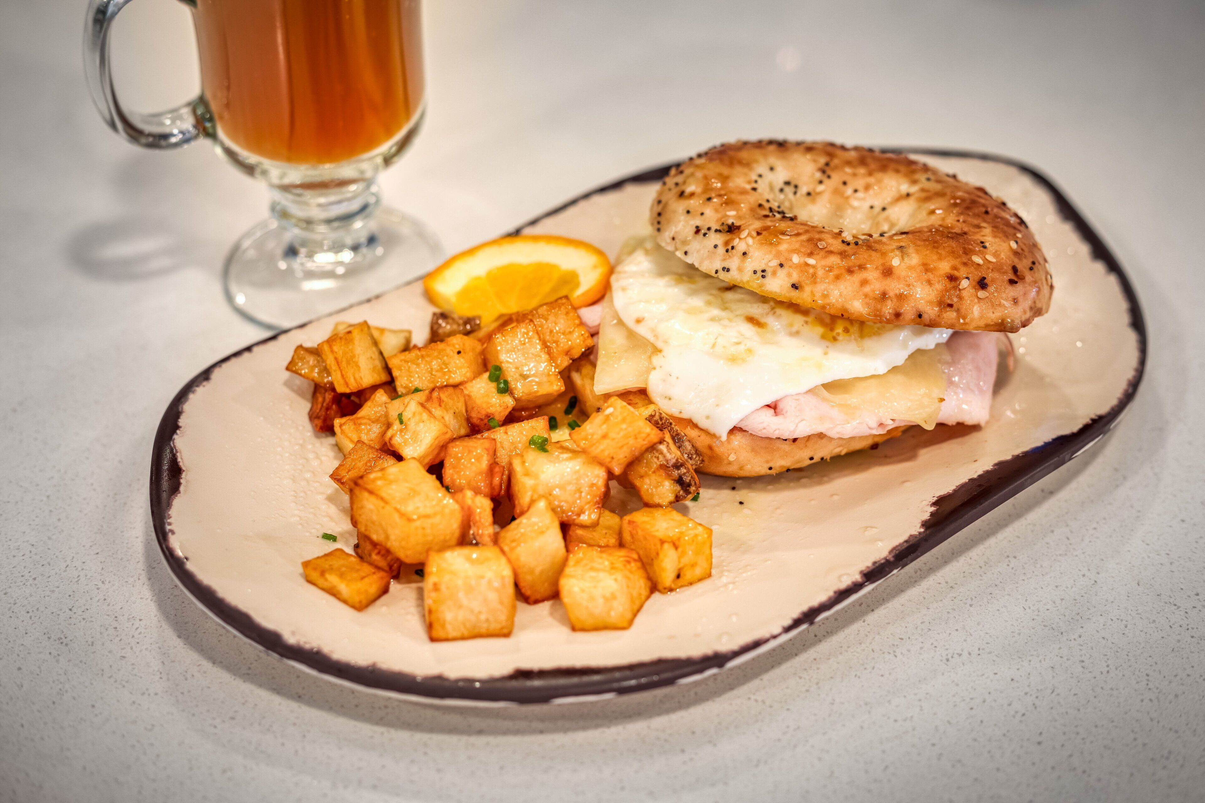 A breakfast plate with hash browns, a sandwich, and a glass of tea.