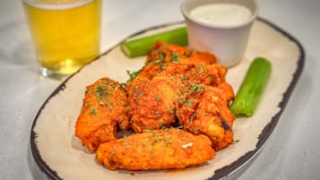 Un plato de alitas de pollo con apio y una salsa al lado.