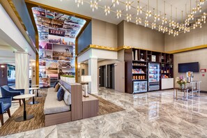 A modern lobby with a seating area, a wall with photos, a minibar, and a TV.