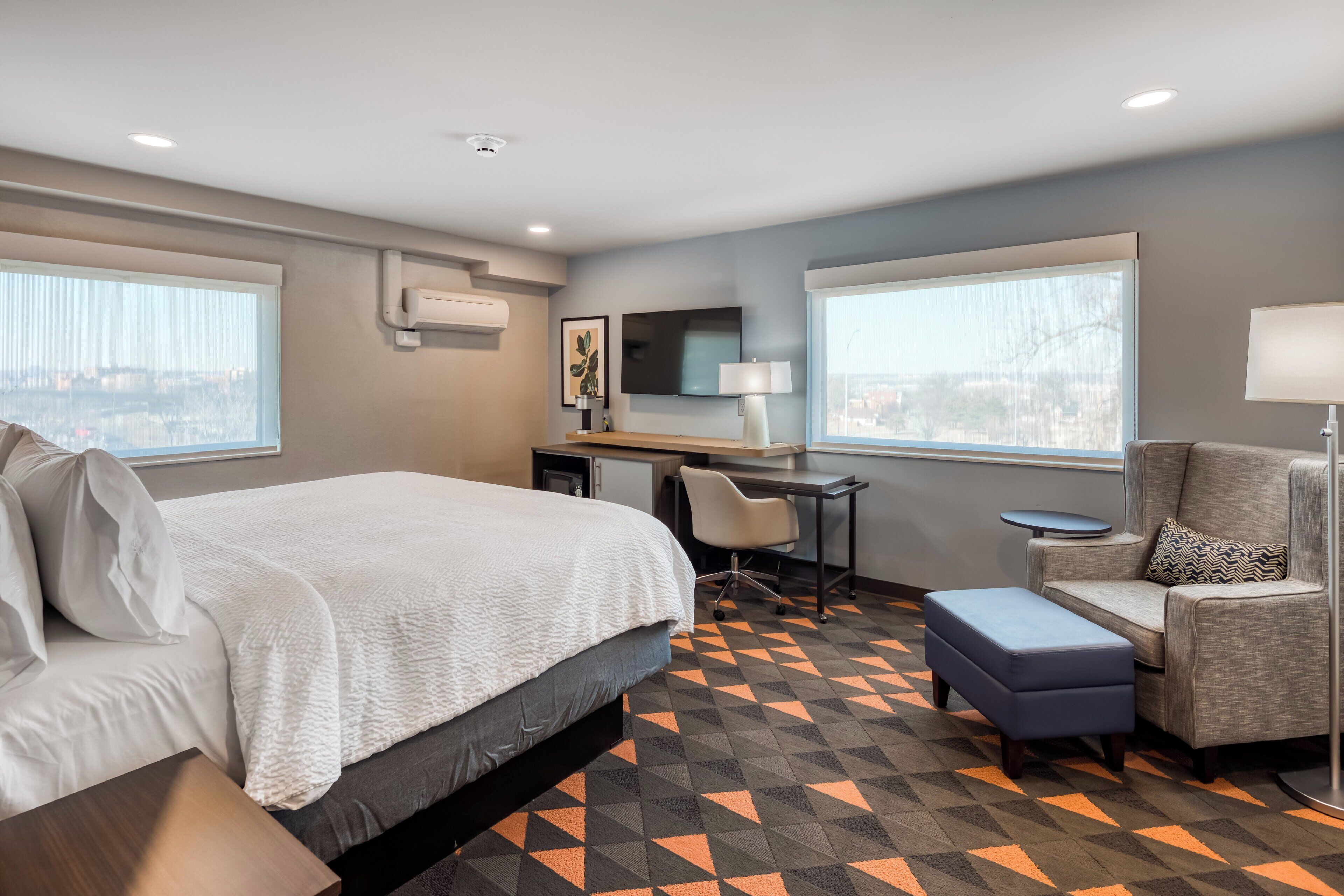 Una habitación de hotel con cama, escritorio, silla y vistas a la ciudad.
