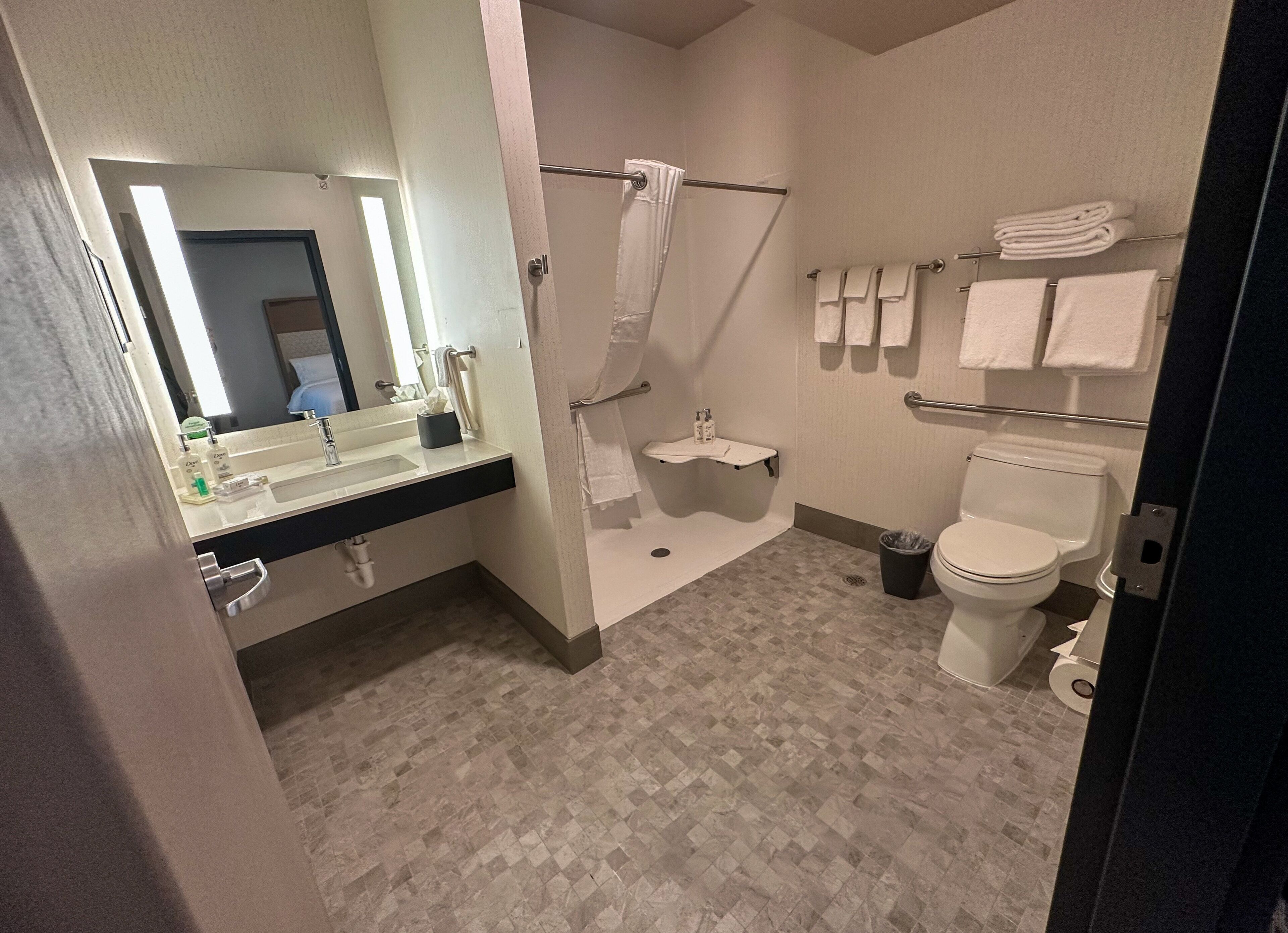 A bathroom with a sink, mirror, shower, toilet, and towel rack.
