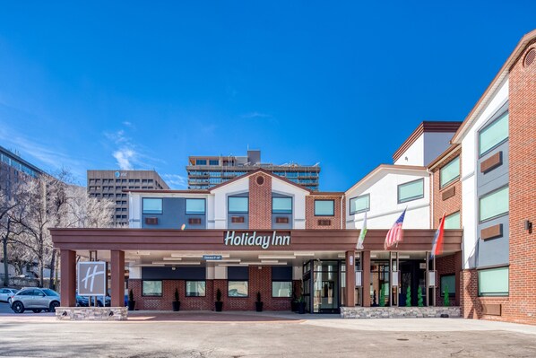 A Holiday Inn hotel with a brick facade, large windows, and an American flag.