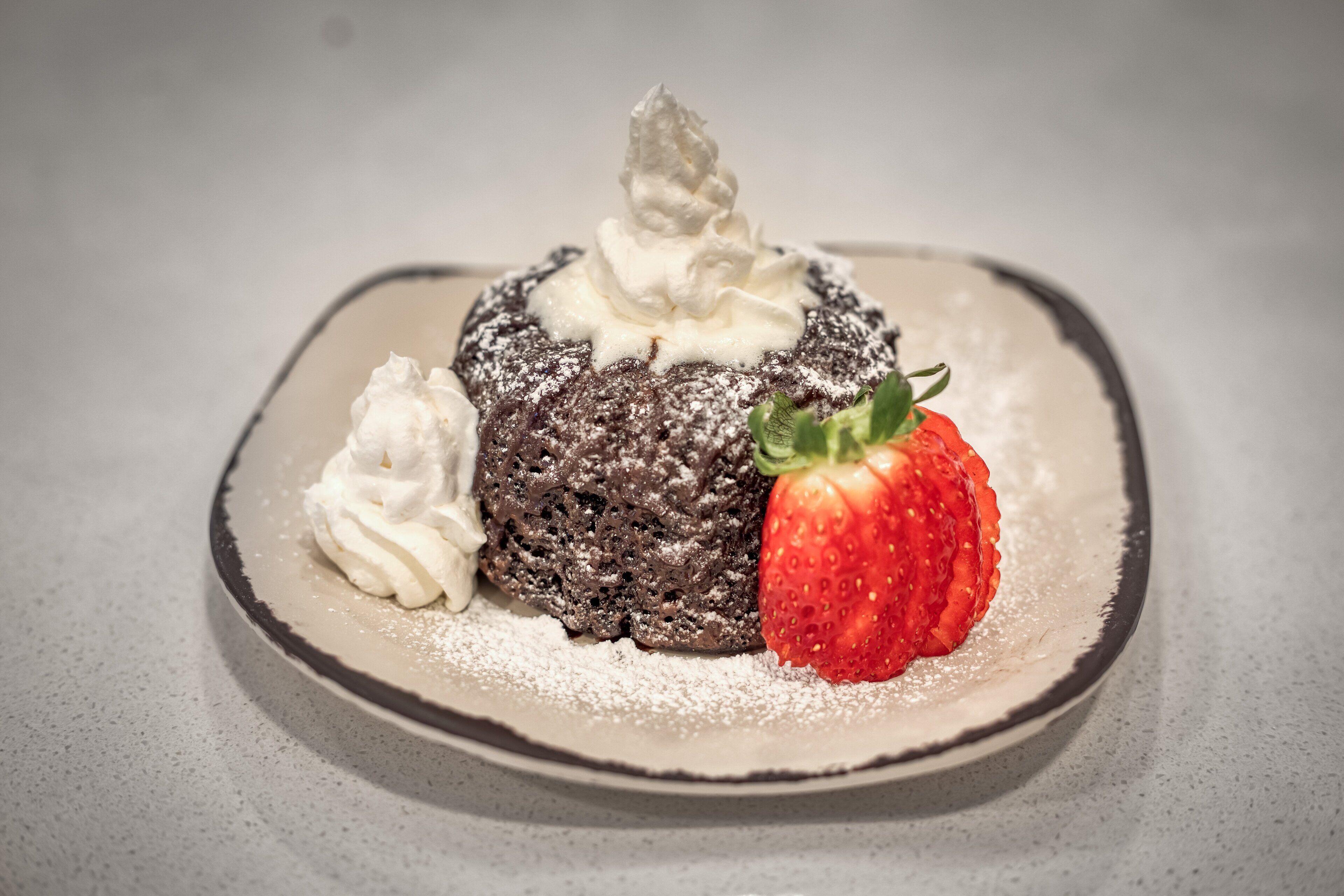 A dessert with whipped cream and a strawberry on a plate.