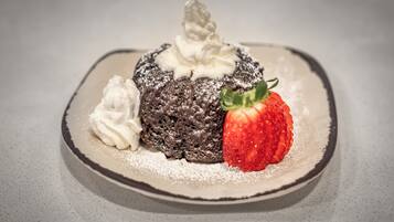 A dessert with whipped cream and a strawberry on a plate.