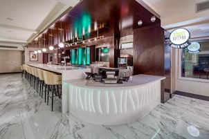 A modern bar area with a marble floor, bar stools, and a counter with a digital ordering system.