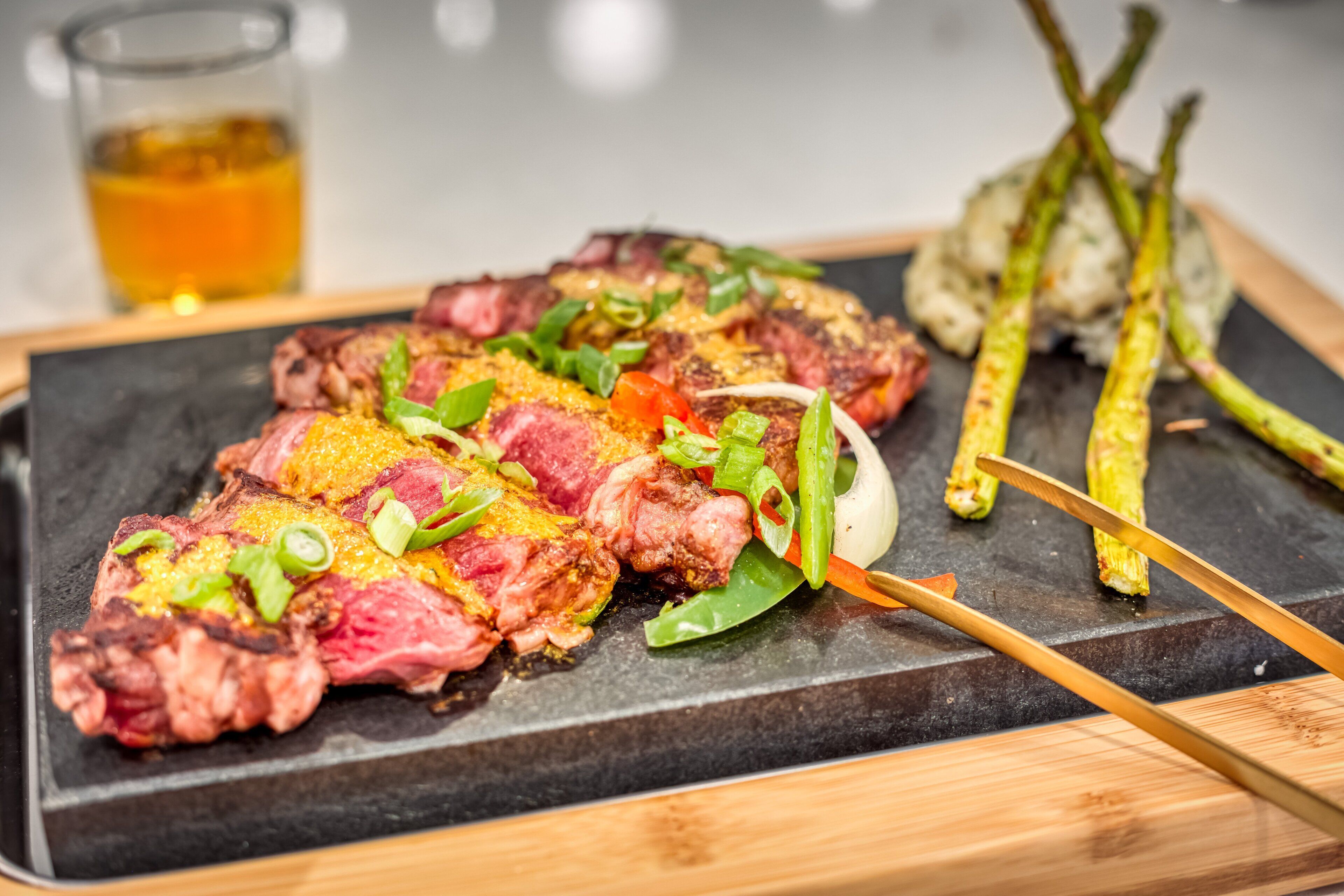 A steak with vegetables on a black plate.