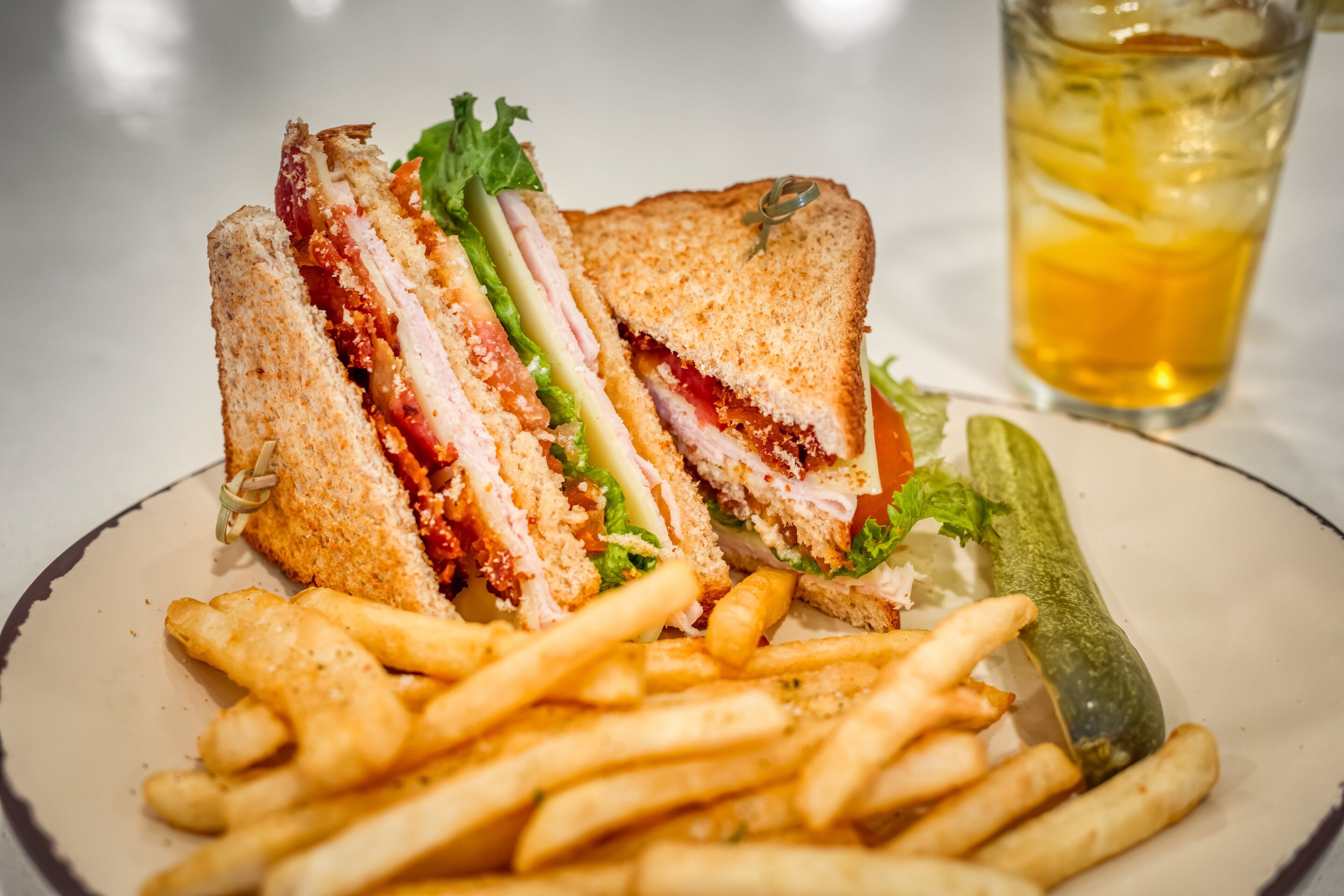 A sandwich cut in half with fries and a pickle on a plate.