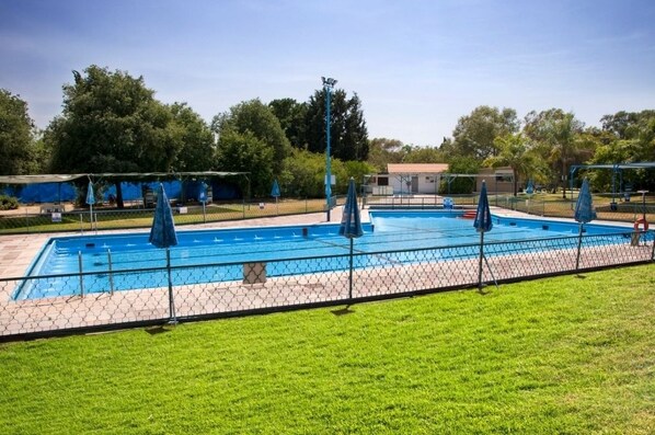 Una piscina al aire libre de temporada, sombrillas