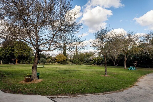 A park with a grassy area, trees, and picnic tables.