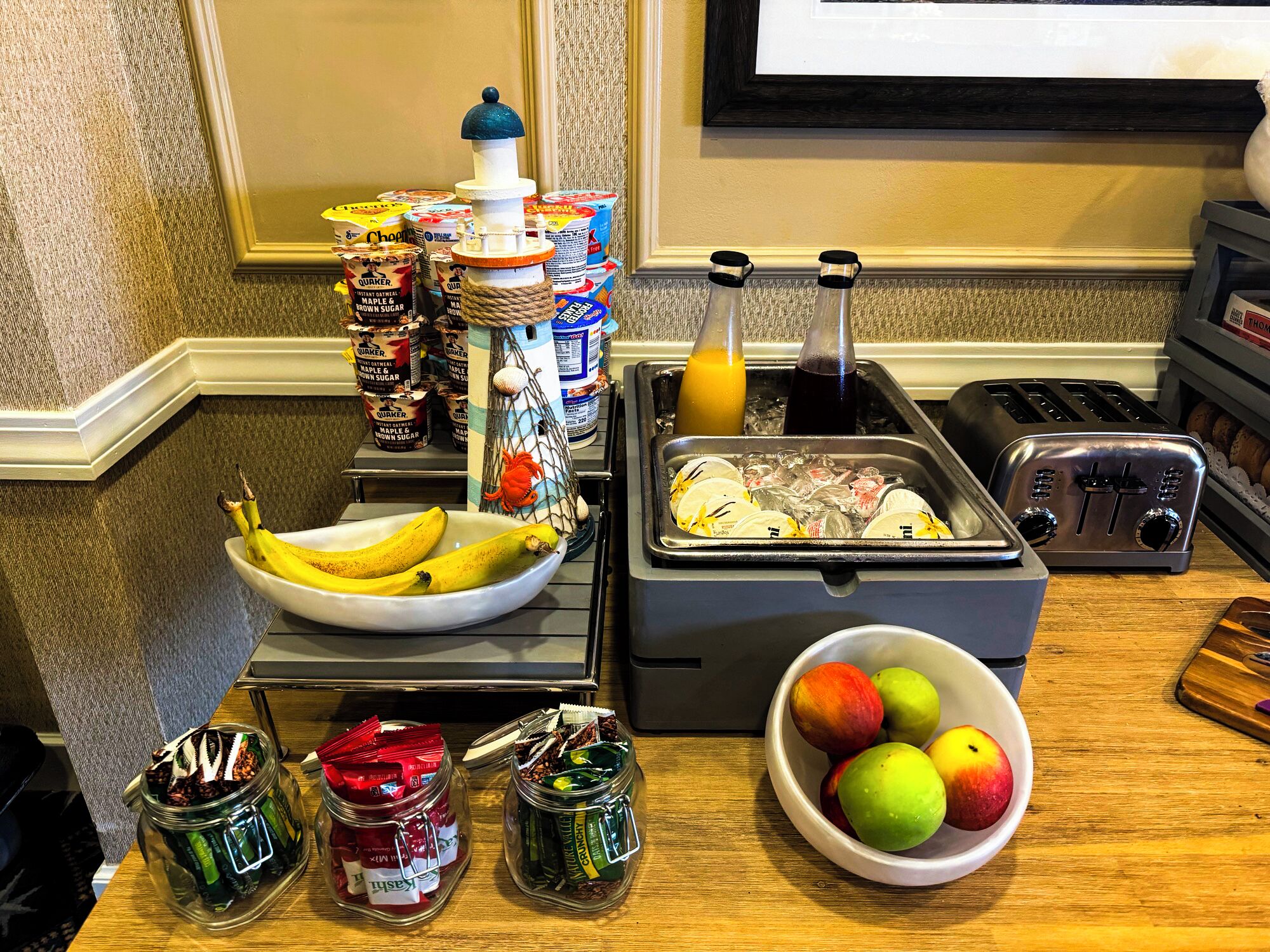 A breakfast buffet setup with various food items, including bananas, apples, and condiments.