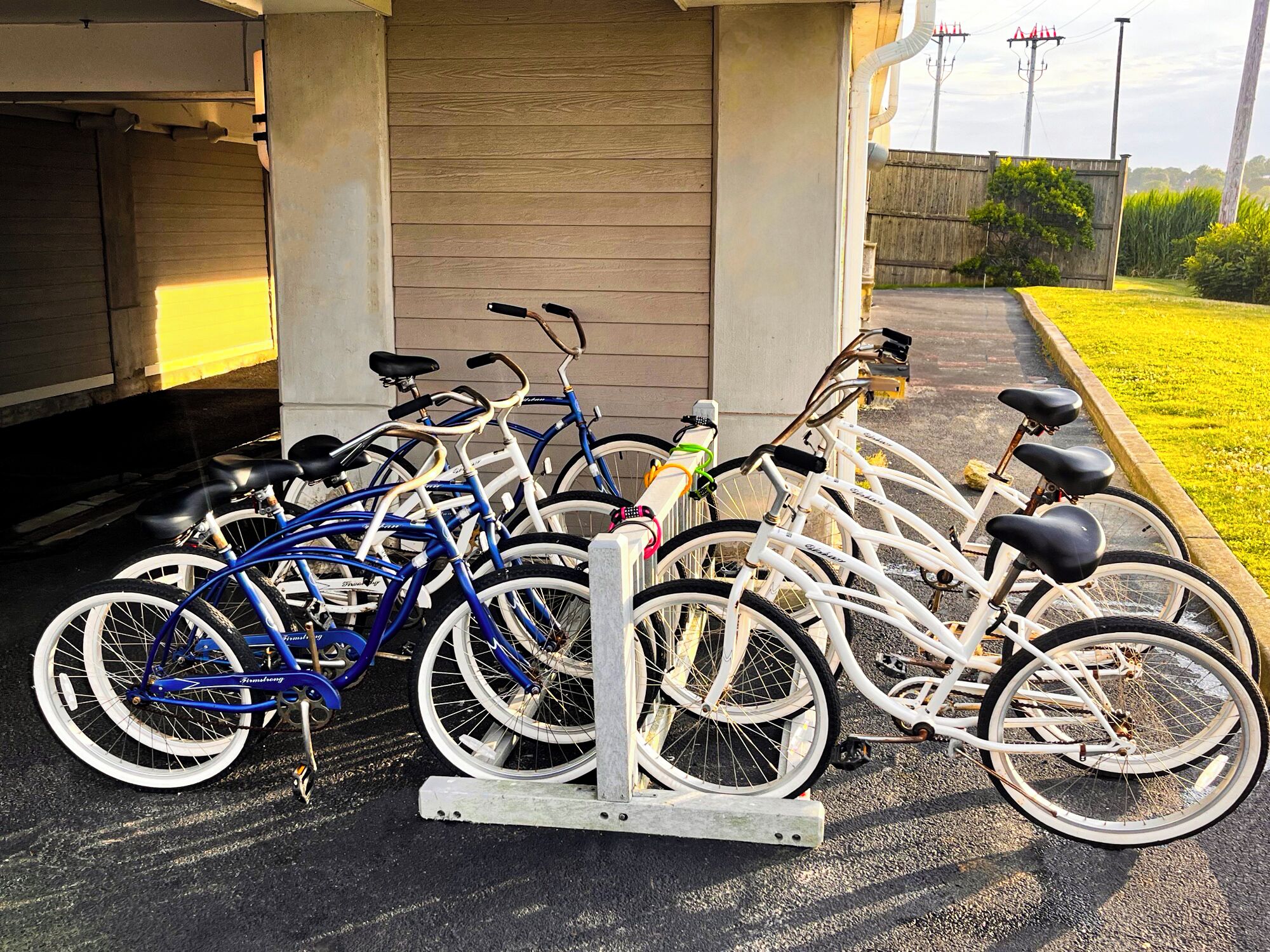 A row of bicycles parked in front of a building with a concrete facade and a wooden door.