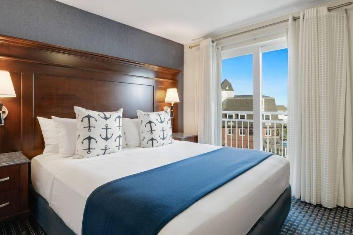 Une chambre d’hôtel avec un grand lit, deux lampes de chevet et une vue sur un immeuble par la fenêtre.