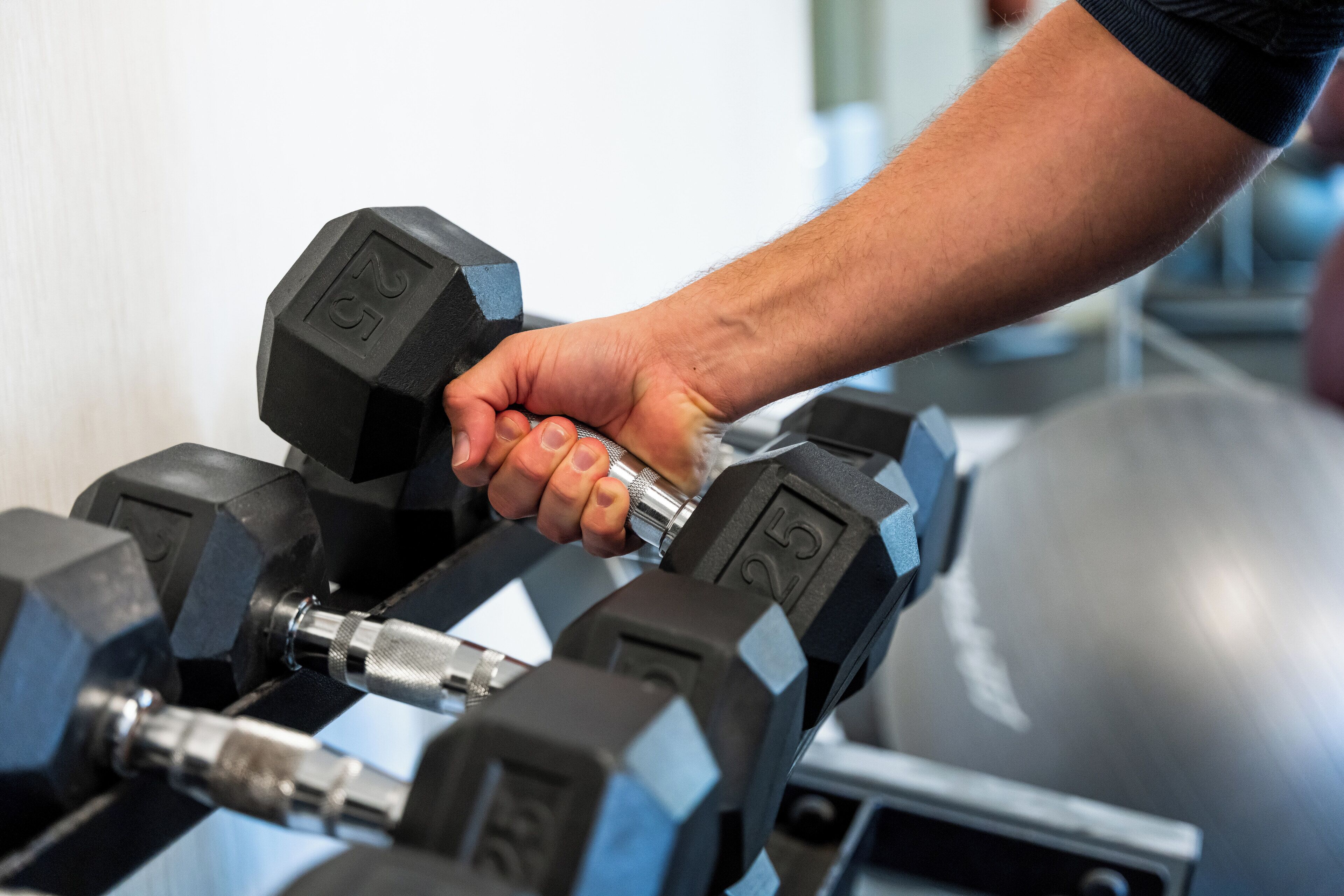 A person lifting a dumbbell with a weight of 25 lbs.