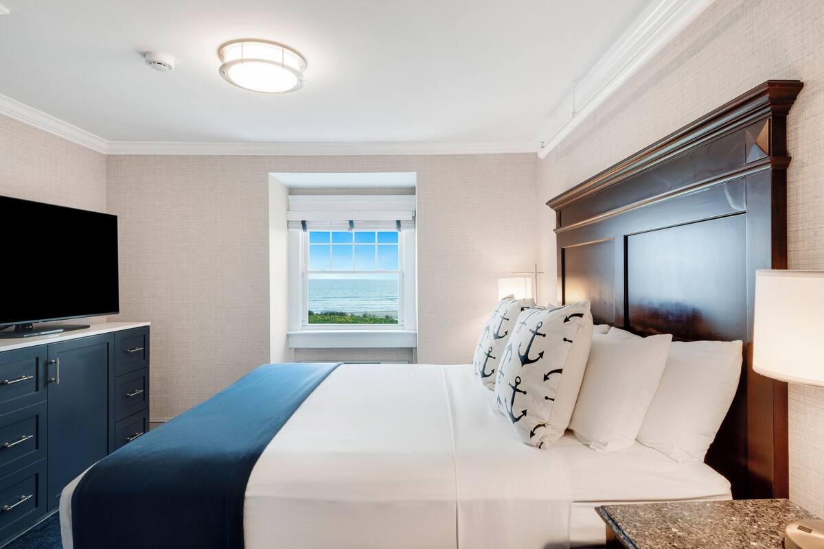 Une chambre d’hôtel avec un lit, une tél évision, une fenêtre donnant sur un paysage agréable et une table de chevet.