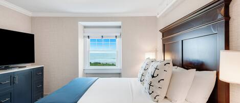 A hotel room with a bed, a television, a window with a view, and a nightstand.