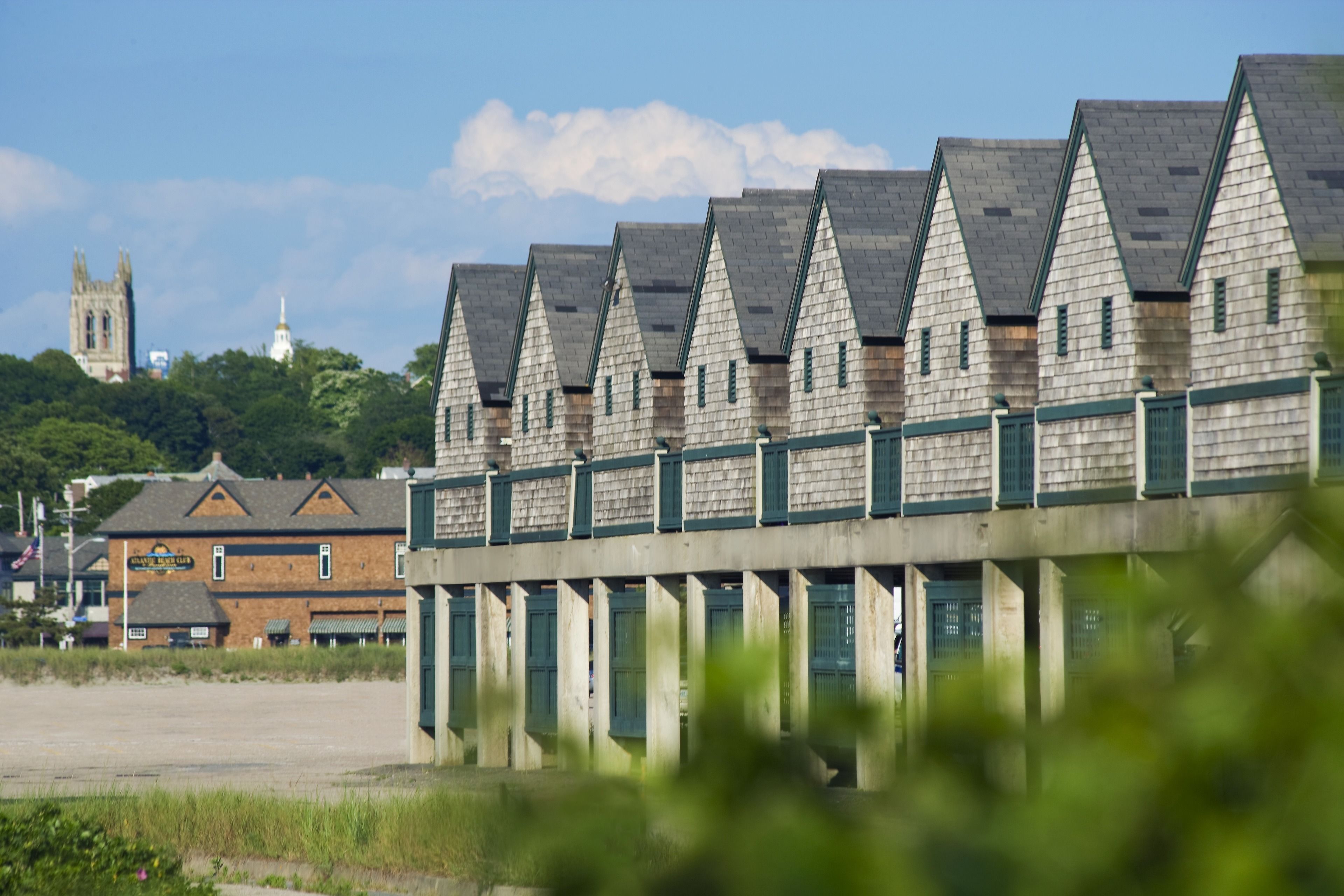 A row of wooden beach huts with a church in the background.