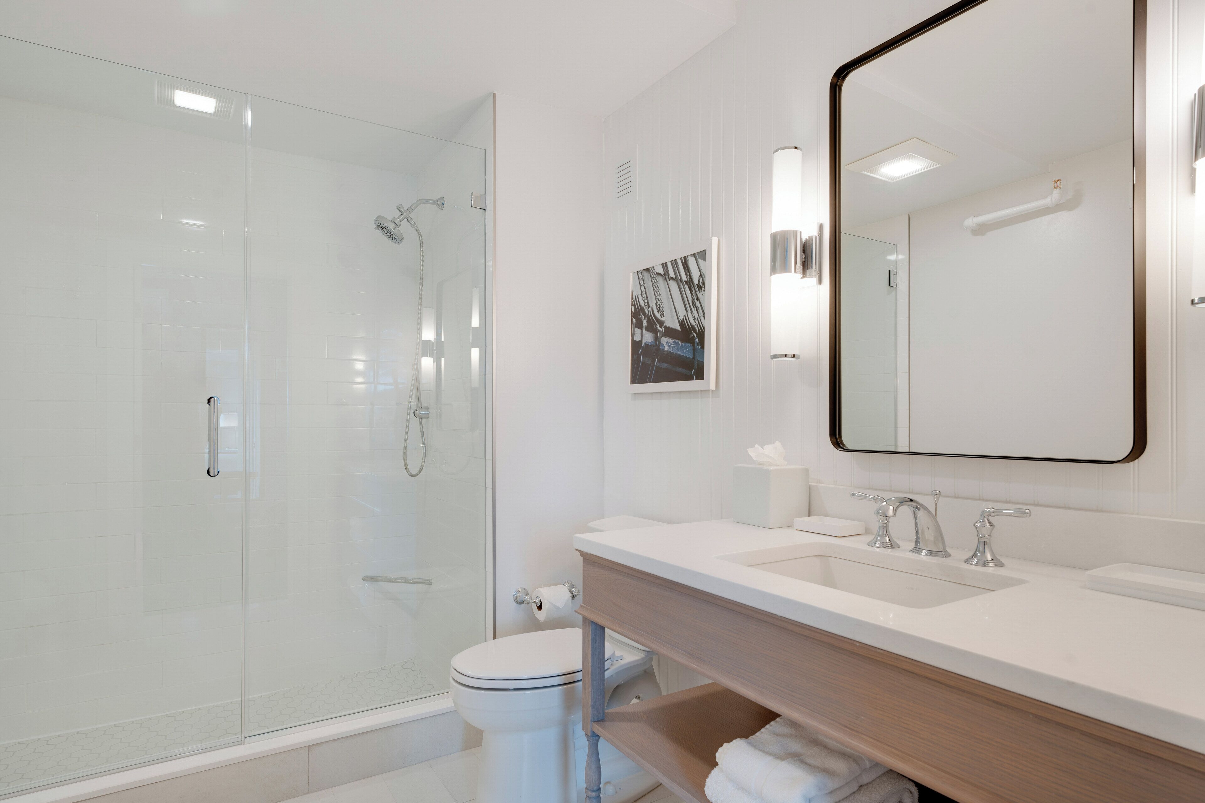 Een moderne badkamer met een douchecabine van glas, een wit toilet en een wastafel met spiegel.