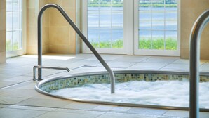 Un jacuzzi con vista a un lago a través de amplios ventanales.