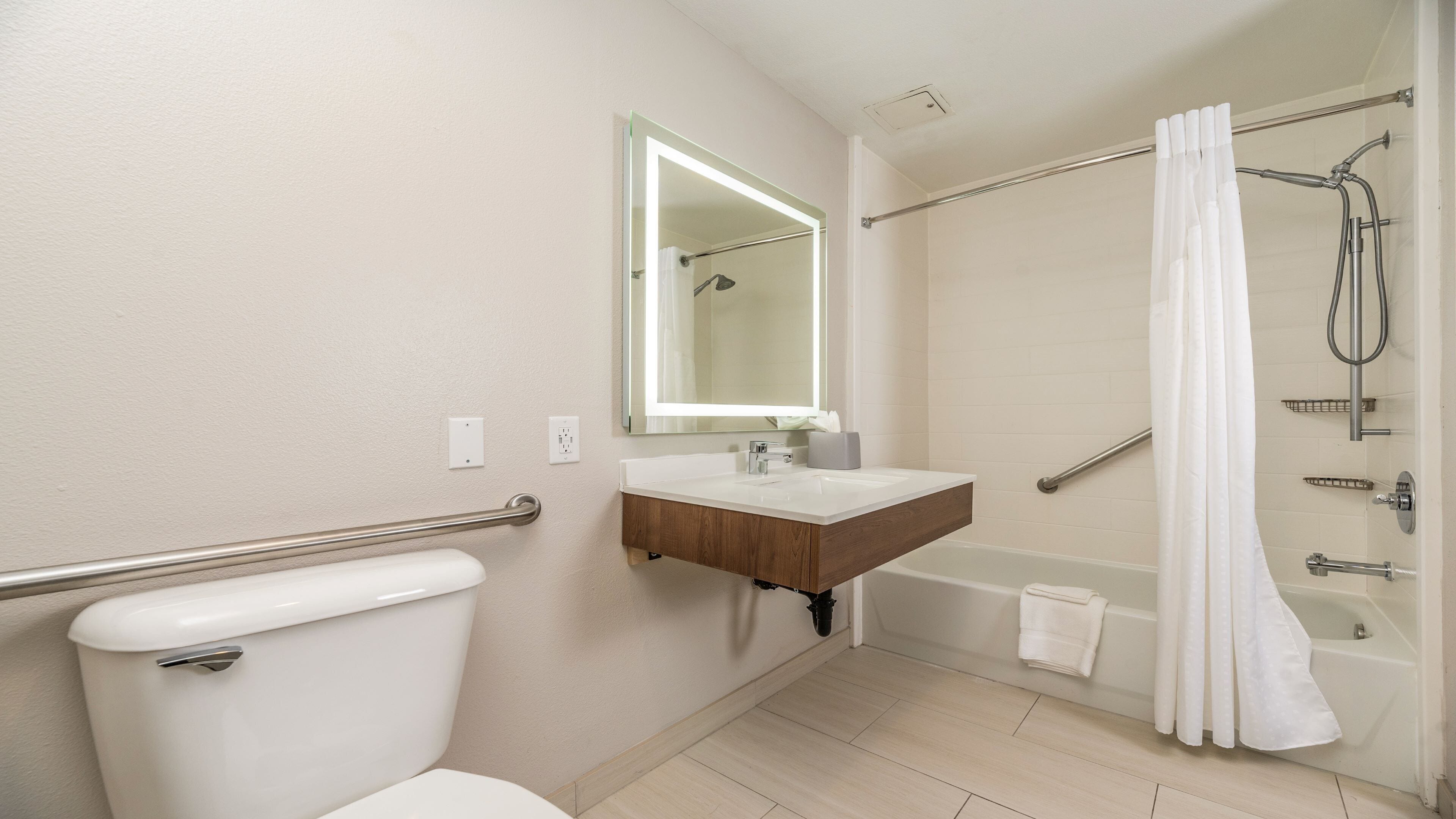 A bathroom with a toilet, sink, mirror, shower, and bathtub.