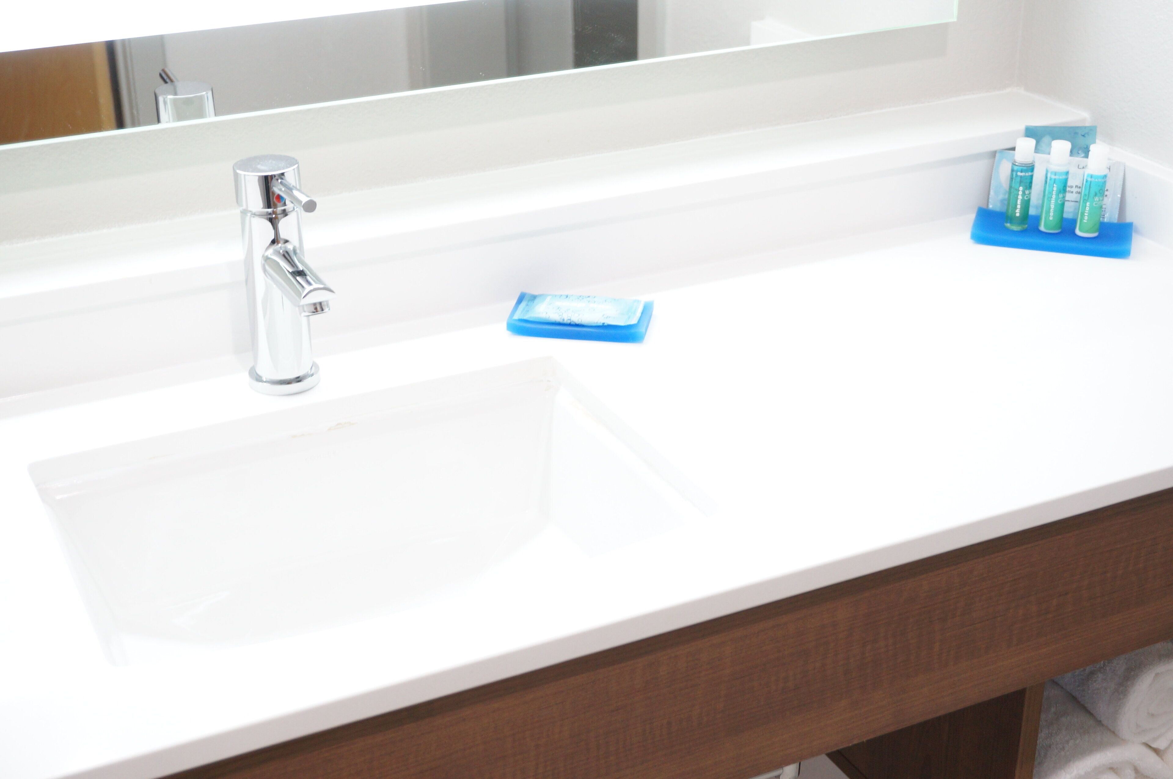 A bathroom with a white sink, a mirror, and toiletries.