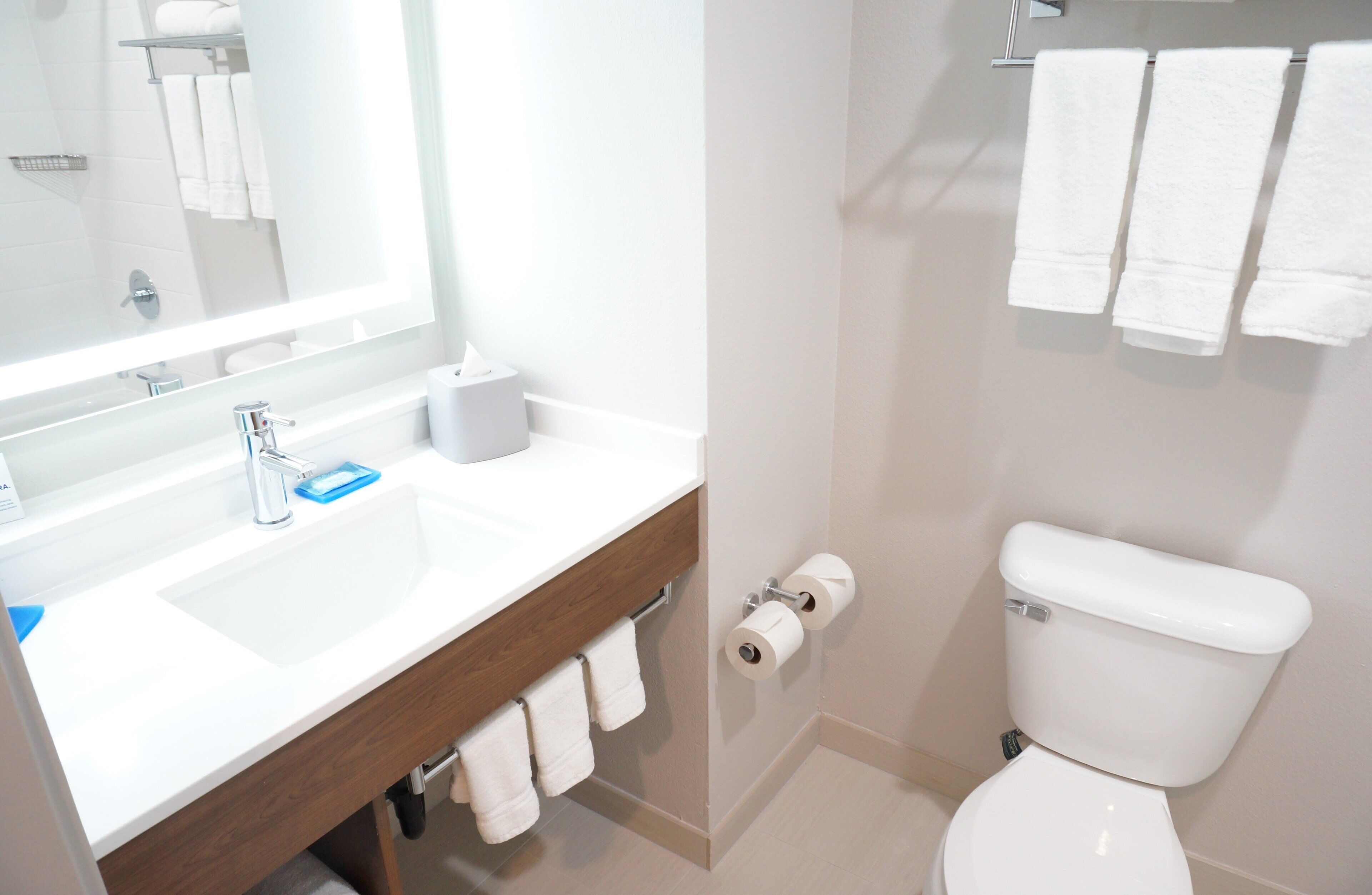 A bathroom with a white sink, mirror, and toilet.