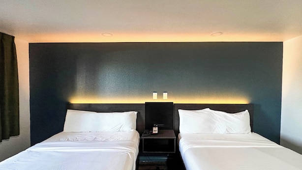Ein Hotelzimmer mit zwei Betten, einer dunklen Akzentwand und einem Nachttisch mit Telefon.