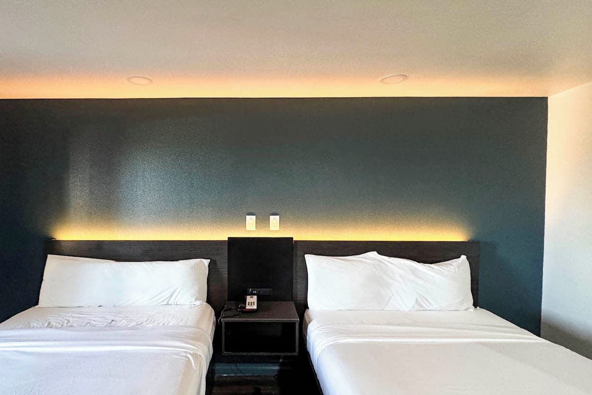 Ein Hotelzimmer mit zwei Betten, einer dunklen Akzentwand und einem Nachttisch mit Telefon.