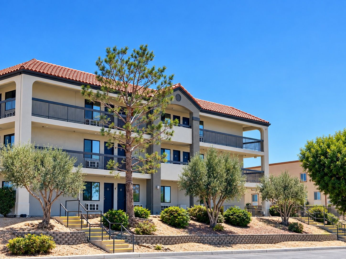 A multi-story building with balconies, a central staircase, and surrounding landscaping.