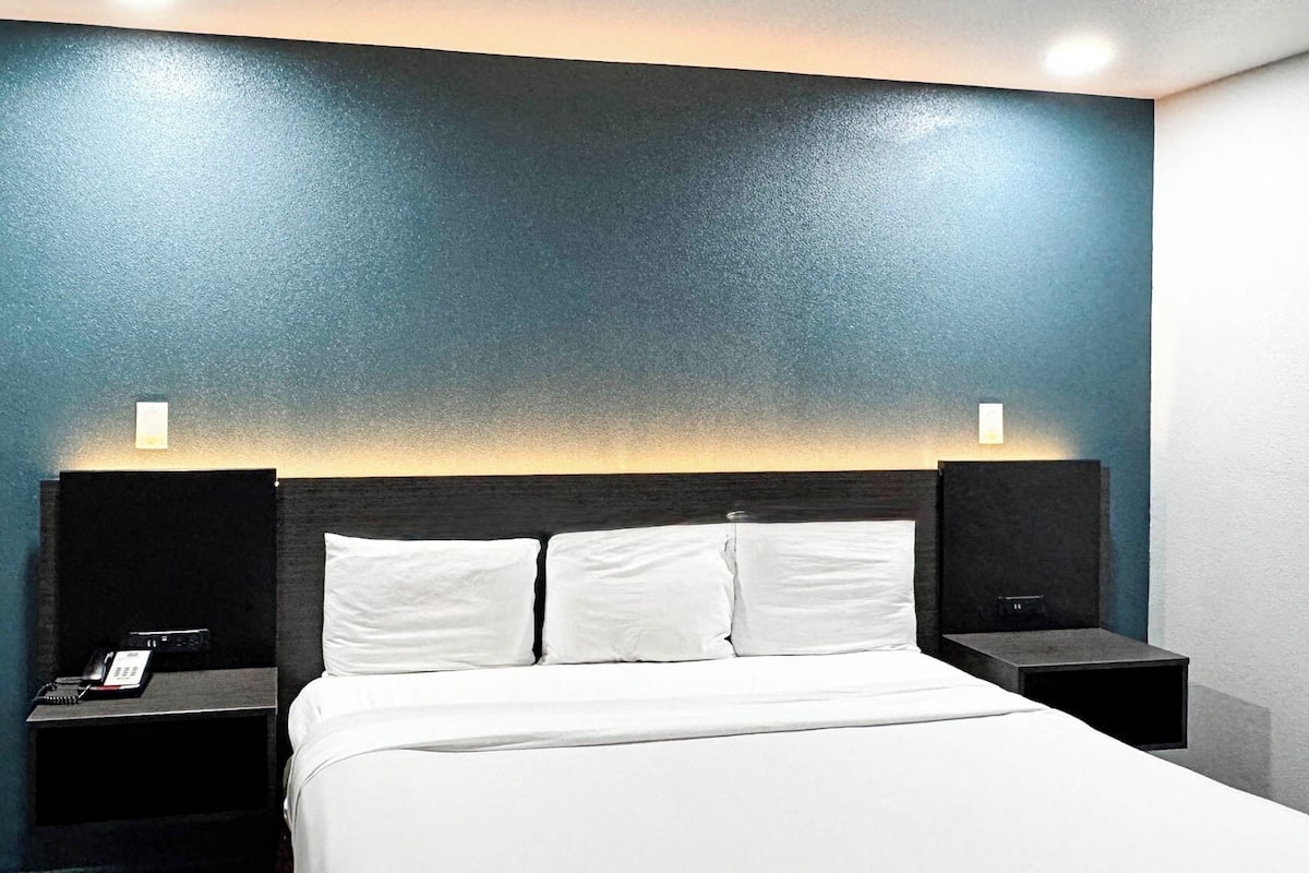 Ein Hotelzimmer mit einem Bett, zwei Nachttischen und einer Wand mit einem strukturierten blau-weißen Design.