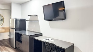 Eine moderne Küche mit Einbaukühlschrank, Mikrowelle und flach an der Wand befestigtem Fernseher.