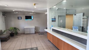 Zona de recepción con mostrador, asientos, televisor y cámara de seguridad.