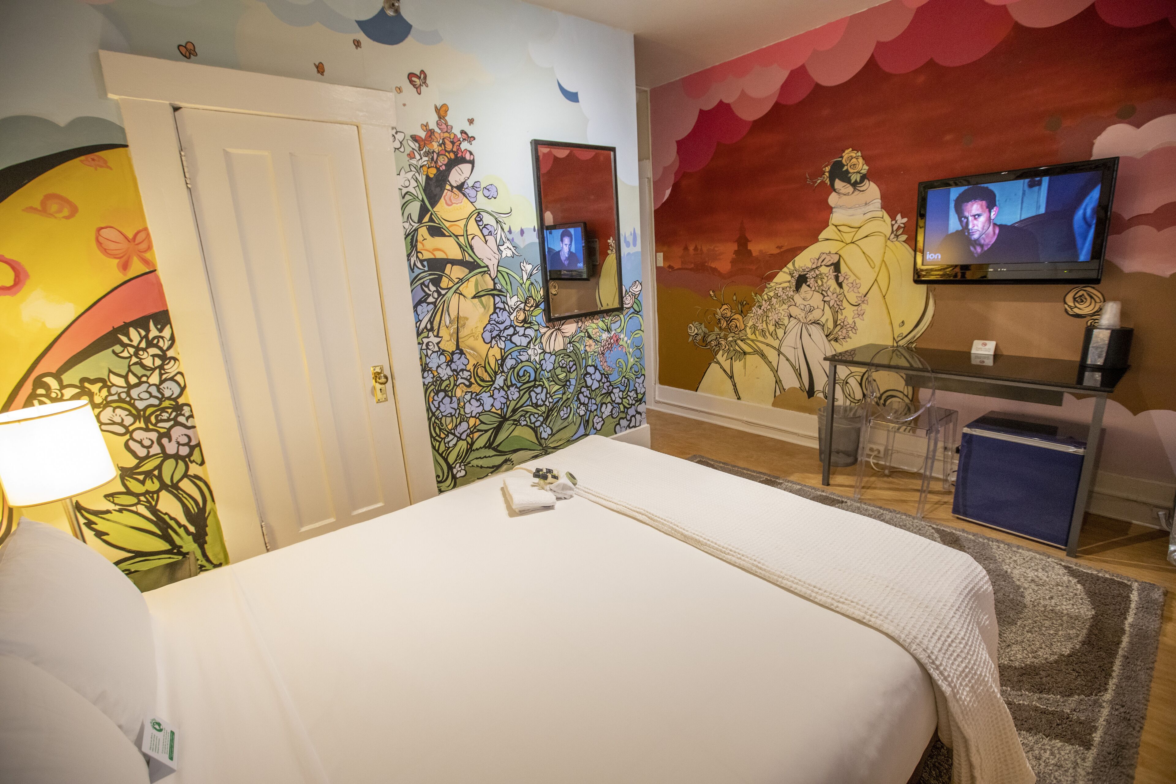 Een hotelkamer met een bed, een televisie, een bureau en een stoel.