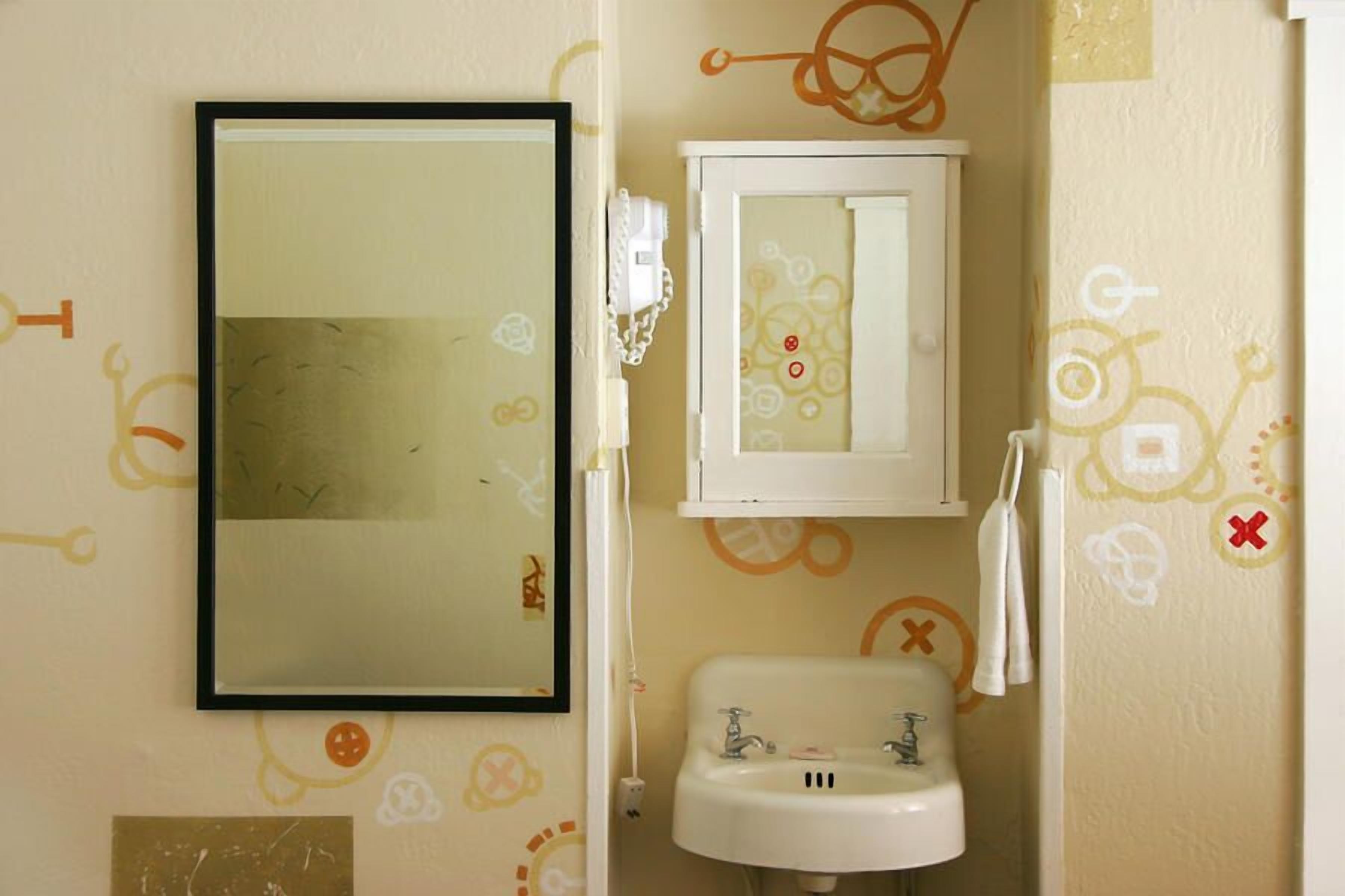 Un baño con espejo, lavamanos y perchero.