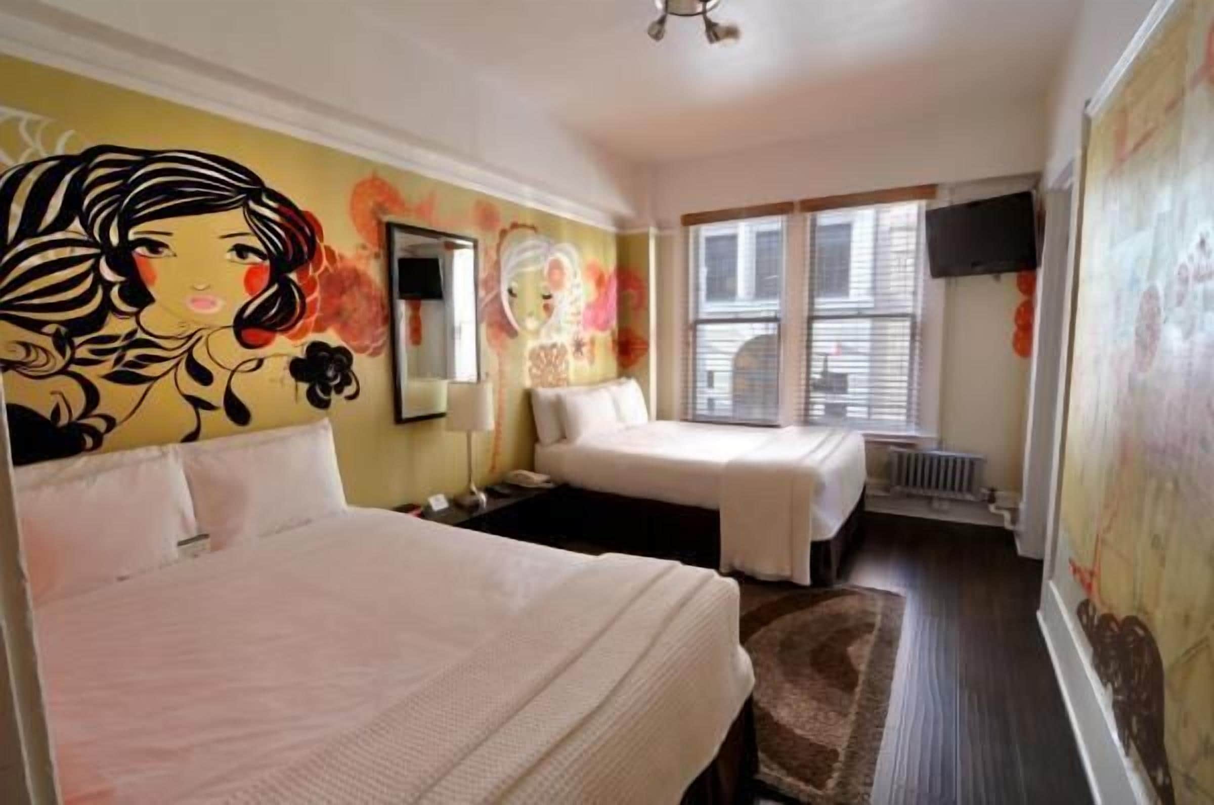 Habitación de hotel con dos camas, un ventanal con persianas, un ventilador de techo y un mural en la pared.