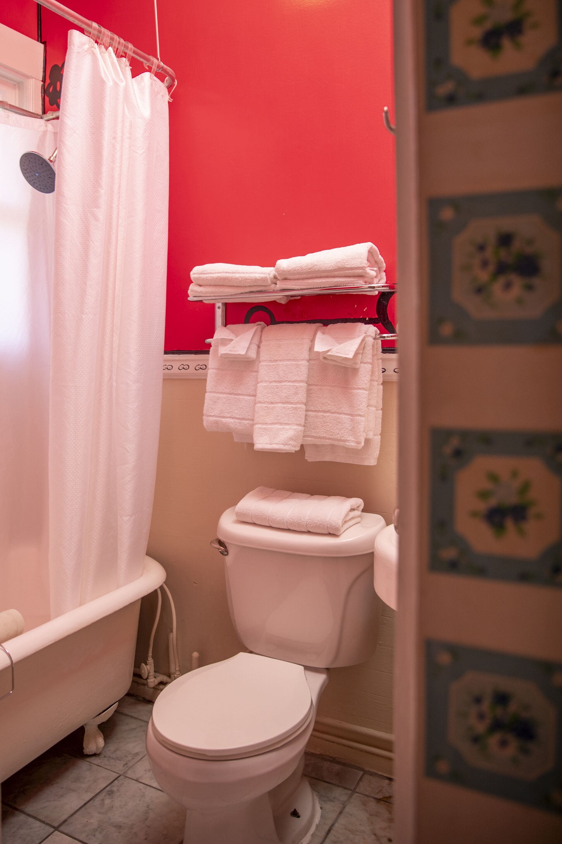 A bathroom with a white bathtub, a white toilet, and a red wall.