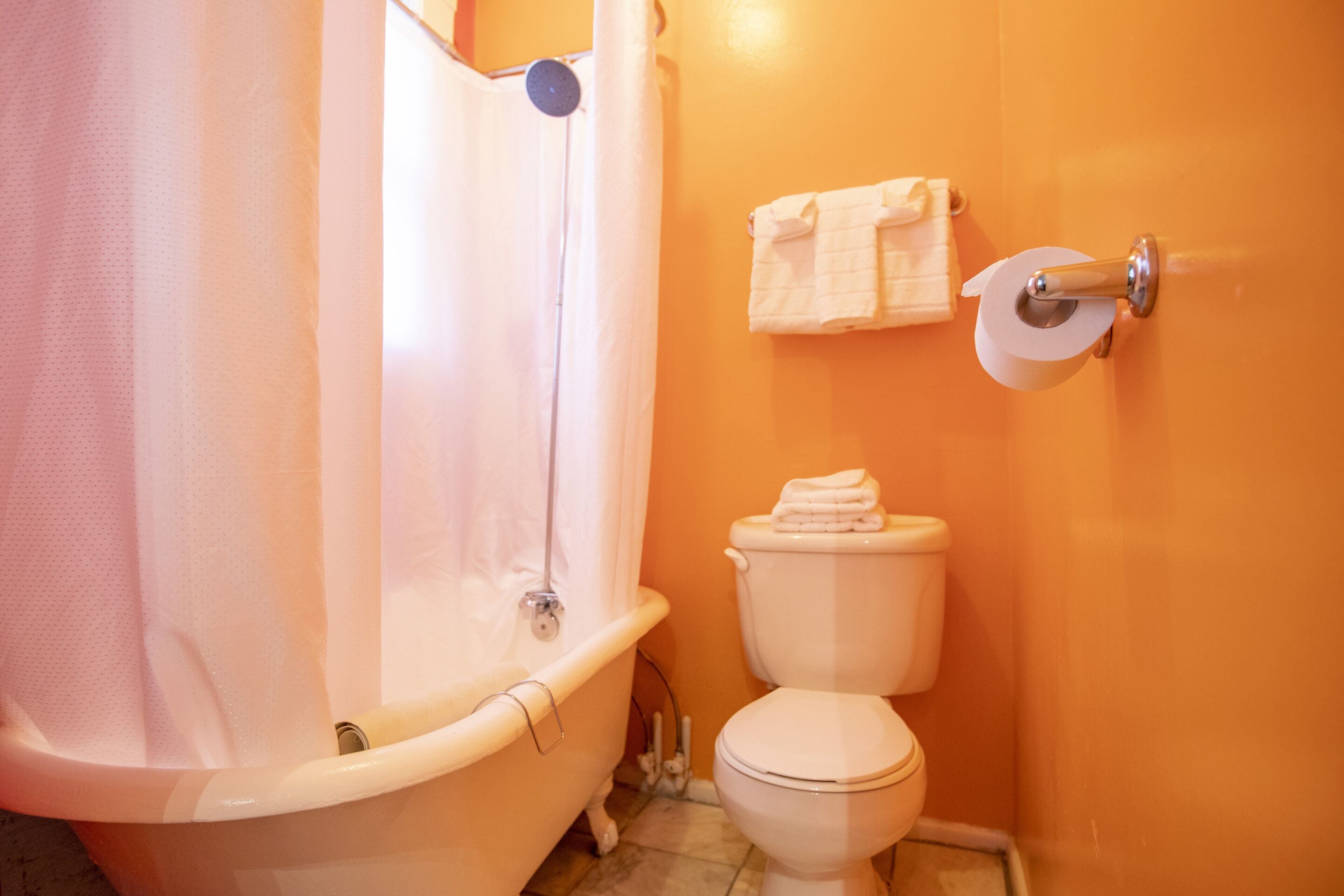 A bathroom with a bathtub, toilet, and a shower curtain.