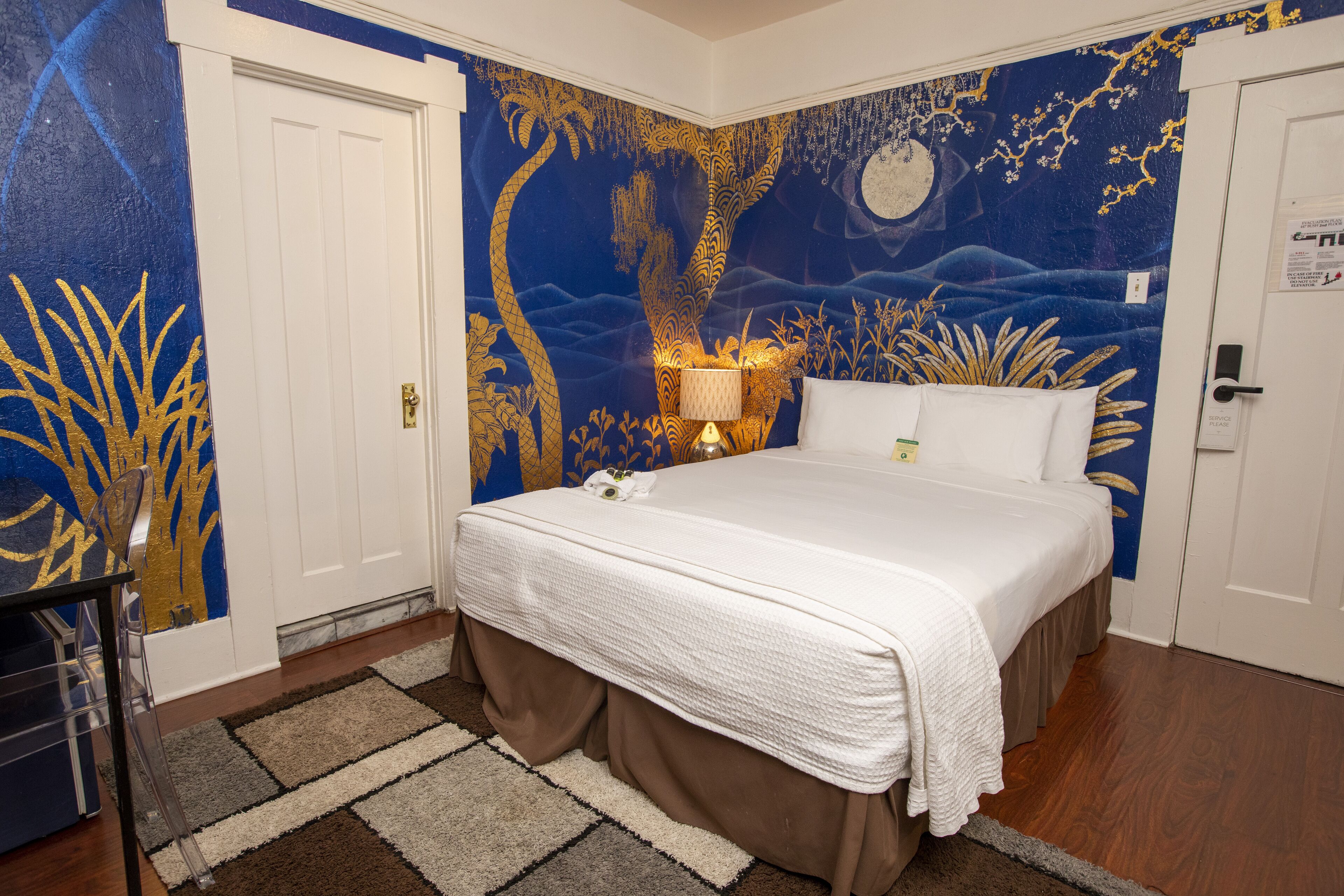 A bedroom with a bed, a nightstand, and a wall mural.