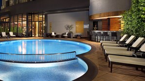 A poolside area with lounge chairs, a bar, and a restaurant. - Surmeli Istanbul Hotel (Istanbul)