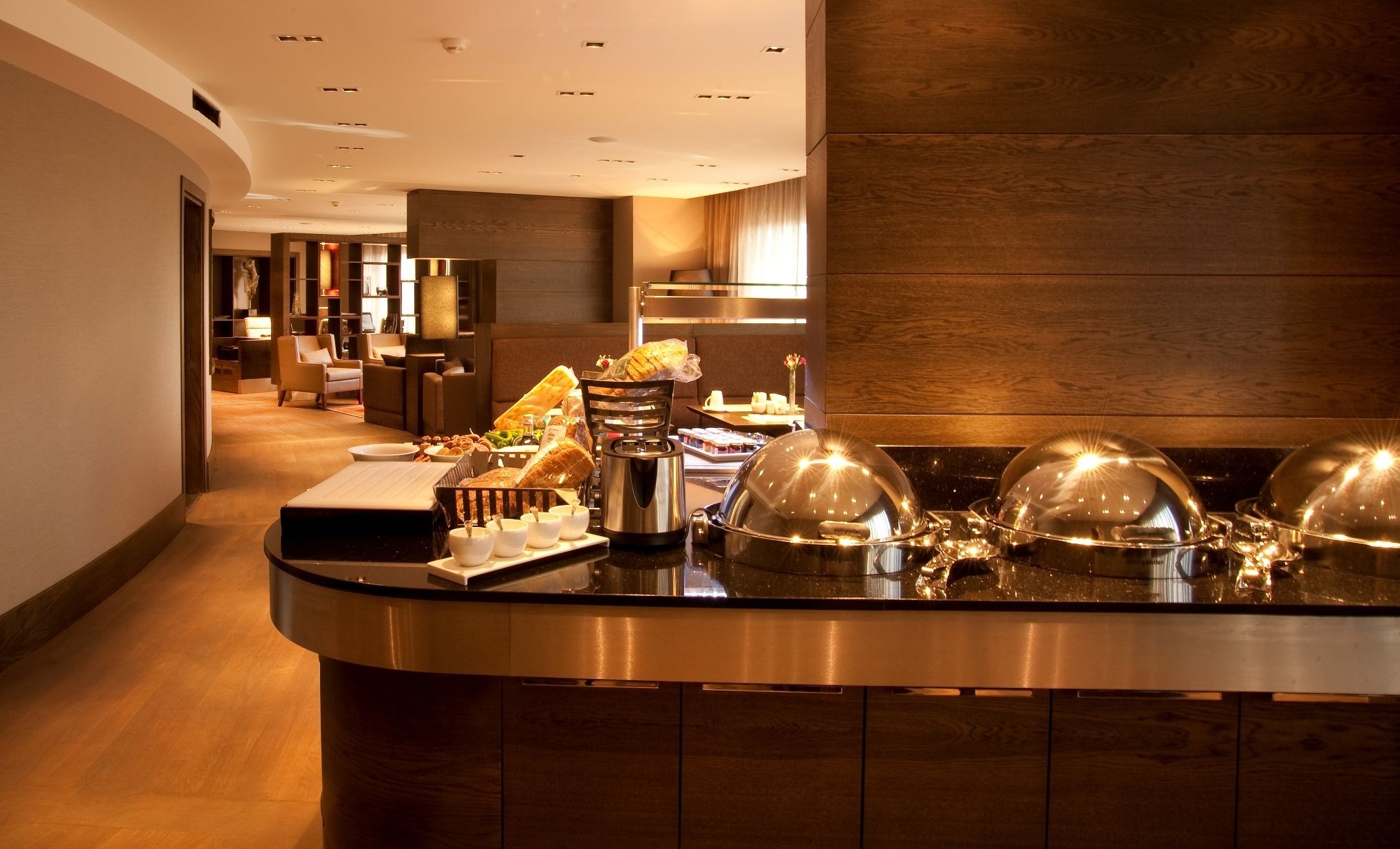 A buffet setup with a variety of food items, a coffee station, and a seating area with chairs and tables.