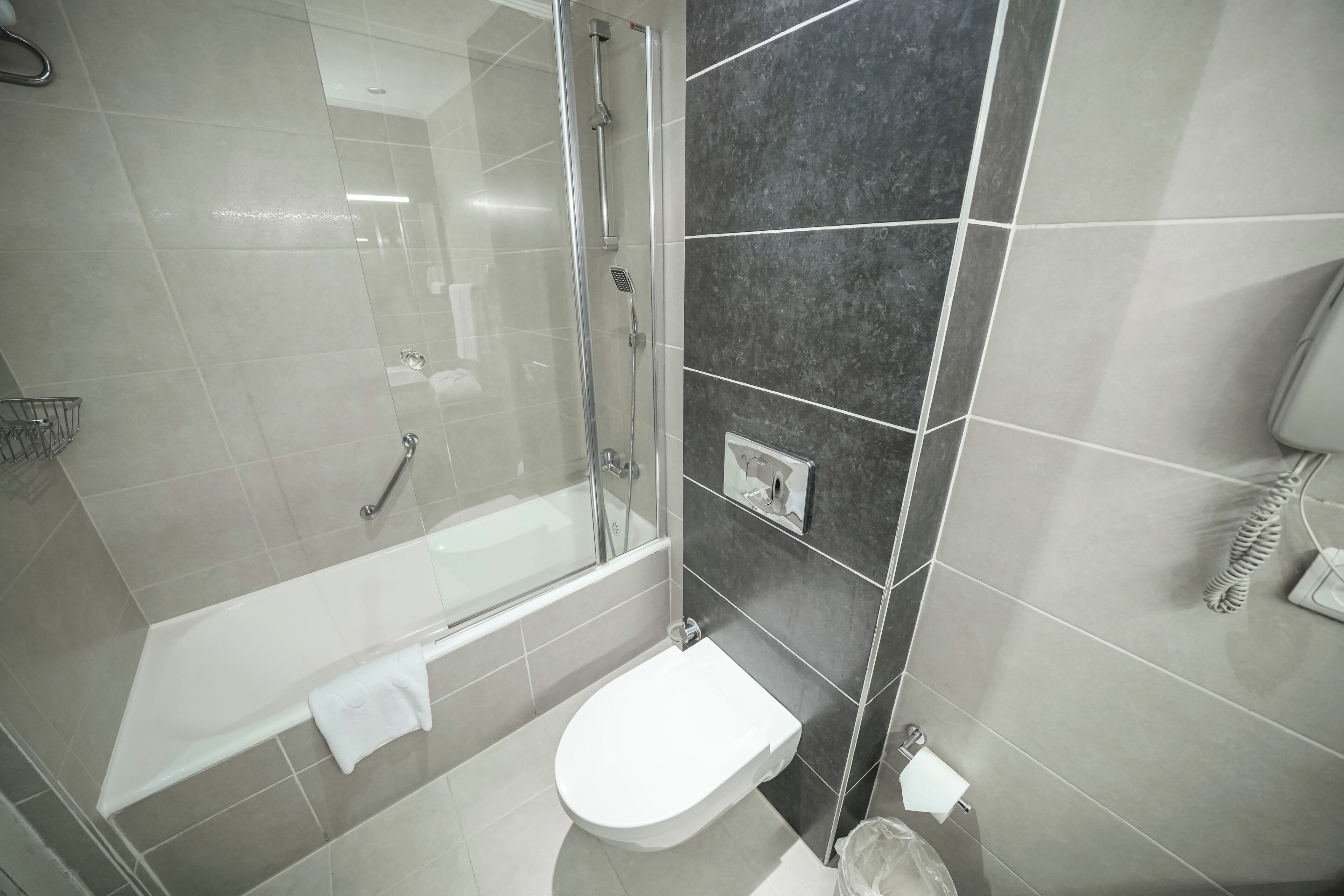 A bathroom with a glass-enclosed shower, a bathtub, and a toilet.